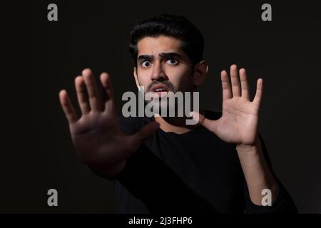 Portrait of a scared young man gesturing with his hands Stock Photo