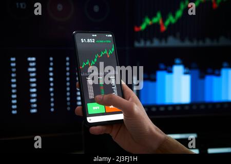 Closeup hand mobile - Person is checking Bitcoin price chart on digital exchange on smartphone, cryptocurrency future price action prediction. Stock Photo