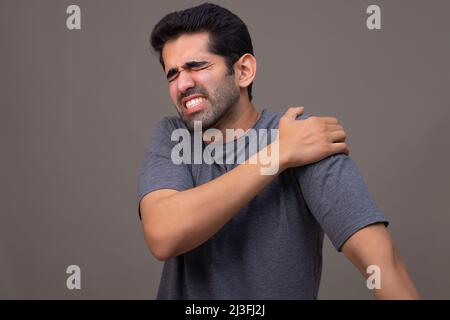 Portrait of a young man suffering from shoulder pain Stock Photo