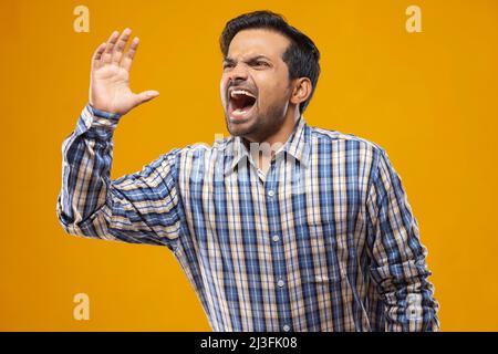 Young man shouting and calling someone far away Stock Photo