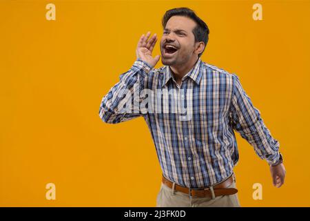 Young man shouting and calling someone far away Stock Photo