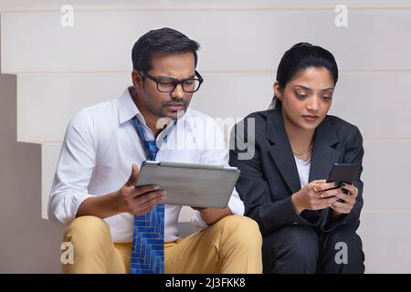 Portrait of a beautiful corporate couple doing office work using digital tablet and smartphone Stock Photo