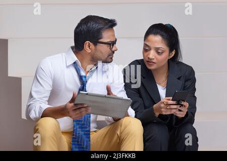 Portrait of a beautiful corporate couple doing office work using digital tablet and smartphone Stock Photo