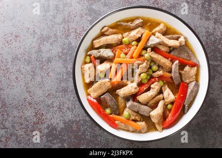 Igado is a popular dish from the Philippines made from pork tenderloin, pork liver, and vegetables closeup in the plate on the table. Horizontal top v Stock Photo