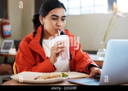 Cant afford to take a real lunch break. Shot of a young female student using a laptop while studying at college. Stock Photo