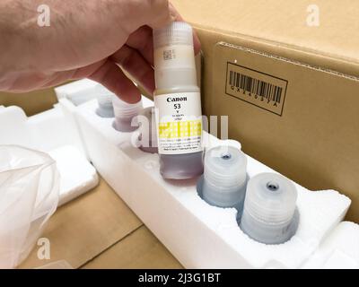 London, united Kingdom - Ap 3, 2022: Holding ink bottle Canon 53 Y for PIXMA G550 single function printer with six refillable dye-based ink tanks, for high quality photo printing Stock Photo
