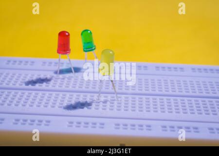 Light emitting diode or LED on a electronic breadboard for projects in engineering and testing. top view of breadboard isolated on yellow background Stock Photo