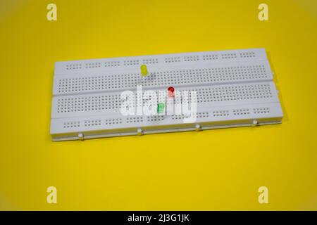 Light emitting diode or LED on a electronic breadboard for projects in engineering and testing. top view of breadboard isolated on yellow background Stock Photo