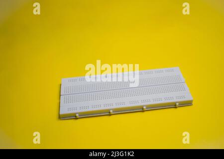 Electronic breadboard isolated on a yellow background. Stock Photo