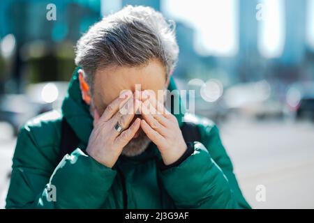 Man standing with hands on head, having a headache Stock Photo
