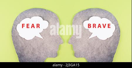 Two people look at each other, speech bubble clouds with the words fear and brave, fearful and courageous mindset, psychology concept Stock Photo
