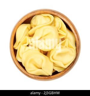 Raw tortelloni pasta in a wooden bowl. Ring-shaped stuffed Italian dumplings with same shape as tortellini, but larger. Stock Photo