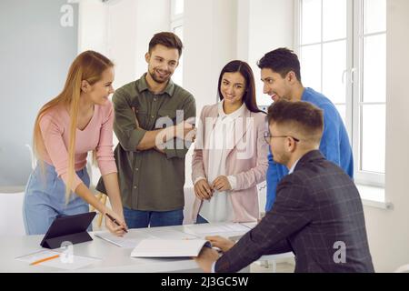 Group of casually dressed businesspeople gathered at the meeting table for discuss the important issues of the new successful startup project. Stock Photo