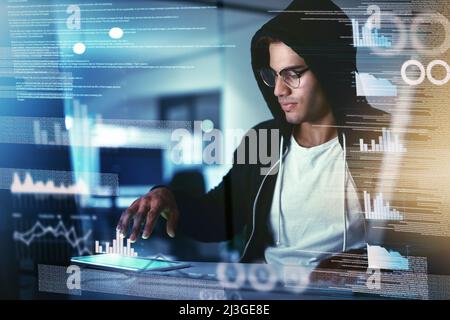 Theres no system he cant crack through. Shot of a young hacker cracking a computer code in the dark. Stock Photo