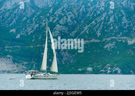 PERAST, MONTENEGRO - JULY 20, 2021: Sailing yacht on the background of mountains Stock Photo