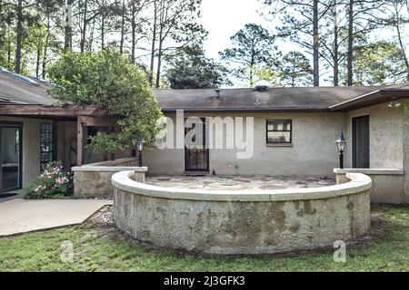 Rear side view of brown spanish style stucco and cinder block 1970's house with a stone circular patio Stock Photo