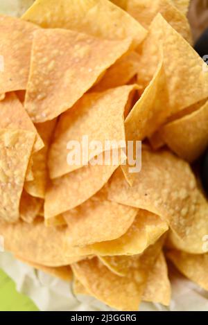Pile of fried crisp tortilla corn chips in a basked on a table for snacking or dipping in salsa at a Tex-Mex restaurant, Fredericksburg, Texas, USA Stock Photo