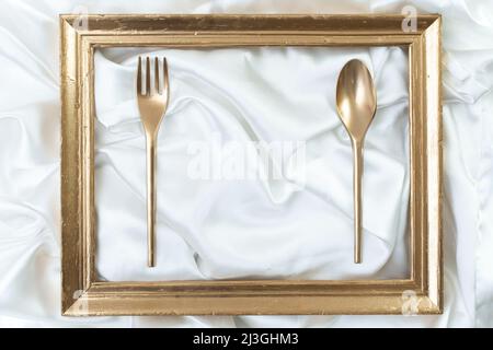 restaurant poster, menu, business card luxury mockup. Creative concept of a dinner setting with golden frame, spoon and fork Stock Photo
