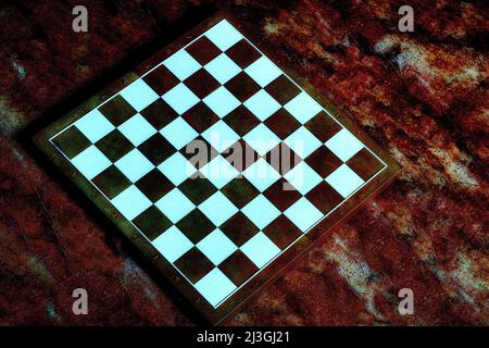 Dark brown chessboard with white cells on a red orange background Stock Photo