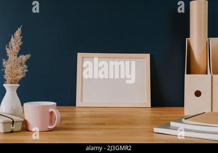 Empty frame on wooden desk and blue wall Stock Photo