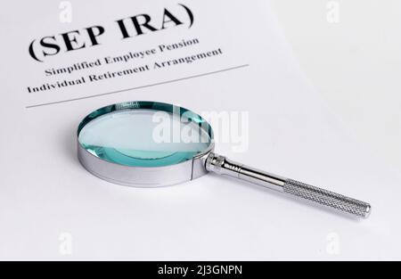 Paper with SEP IRA words and magnifying glass. Simplified Employee Pension Individual Retirement Arrangement. Analysis and planning of contributions. Business and finance concept. High quality photo Stock Photo
