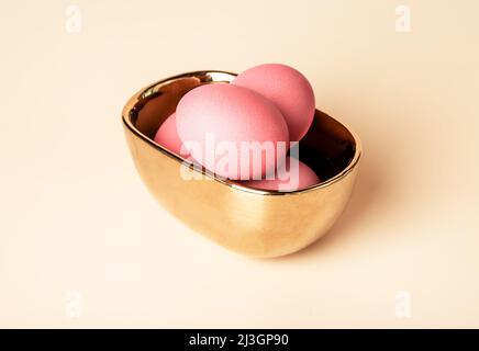 Pink dyed Easter eggs in golden bowl. Celebration of Christian feast concept. High quality photo Stock Photo