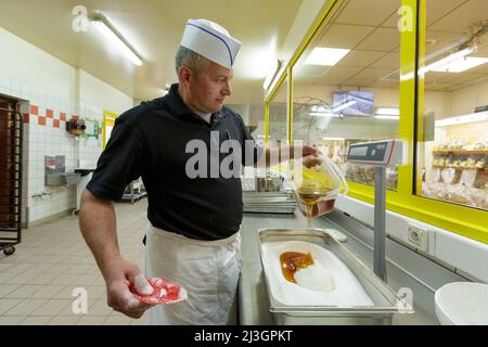France, Meuse, Commercy, Thierry Zins pours the honey on the sugar for the preparation of the madeleine dough in the shop and madeleine workshop of Commercy La Boite à Madeleines of the Zins brothers, madeleiniers since 1951 Stock Photo