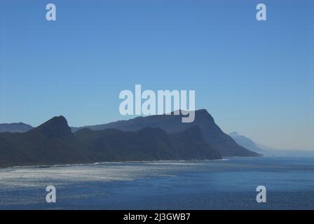 A misty day creates a beautiful panorama of abstract mountain shapes along the coastline of the Cape Peninsula in South Africa. Stock Photo