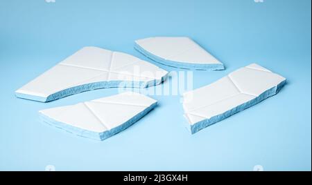 Pieces of broken ceramic tile on blue background. Concept of despair and hurt in psychology. High quality photo Stock Photo