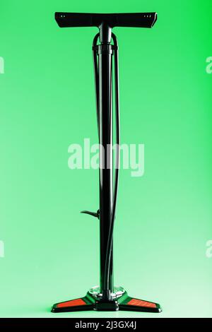 Black bicycle manual air pump for pumping wheels on a green background with a vertical composition Stock Photo