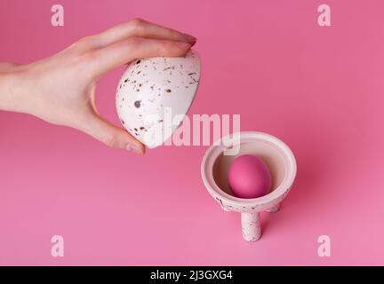 Woman opening cup with Easter pink egg. Religious holiday concept. Traditional feast symbol in beautiful server. High quality photo Stock Photo