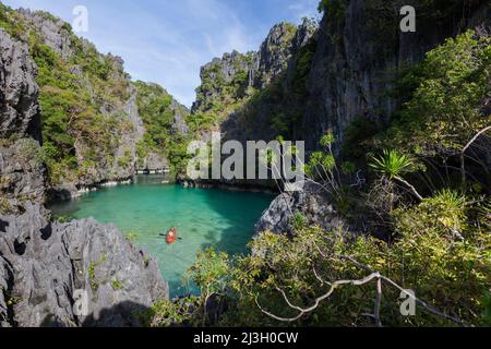 Philippines, Palawan, El Nido, Bacuit Archipelago, isolated tourists paddling in a sea kayak, on Miniloc Island's Small Lagoon, surrounded by karst cliffs Stock Photo