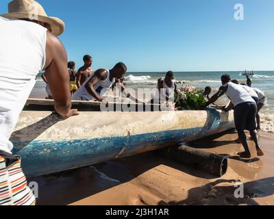 Fishermen putting canoe into the sea for delivery of Iemanjá's gifts at Boca do Rio beach in Salvador, Bah Stock Photo