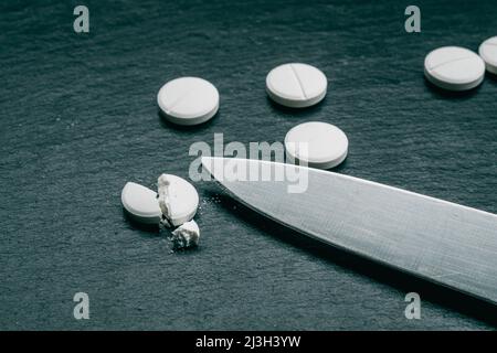 MDMA Pill known as ecstasy  E  or molly, is a psychoactive drug primarily used for recreational purposes. MDMA drugs and knife on black background Stock Photo
