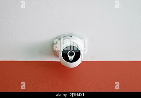 Home Security Camera on Red and White Ceiling Stock Photo