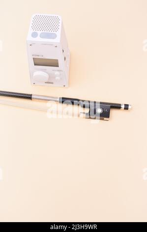 Digital metronome and violin bow on a beige table surface - Tempo and beat concept Stock Photo