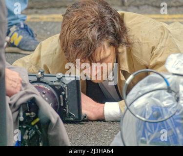 Glasgow, Scotland, UK 8th April, 2022.  West Nile street was closed off today as snow and hail fell down on Ira thriller borderlands filming in the city centre. Colin Morgan lies face down in the cold and wet for a close up  between snow showers and hides under a reflector during them.. Credit Gerard Ferry/Alamy Live News Stock Photo