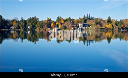 Reflection of the cottages and fall leaf colour in the lake district, Ontario, Canada. Stock Photo