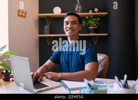 A young Asian man smiles at the camera in his office Stock Photo