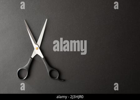Basic conceptual hairdressing background with scissors on a black background and space to write. Top view. Horizontal composition. Stock Photo