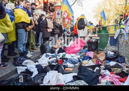 London, UK. 07th Apr, 2022. Protesters wrapped in Ukrainian flags stand next to clothing and other items thrown on the ground during the protest in solidarity with Ukraine outside the Russian Embassy in London. Hundreds of people gathered outside the embassy and dumped pans, clothing, toys, appliances and other household items, in response to the looting by Russian soldiers in Ukraine. (Photo by Vuk Valcic/SOPA Images/Sipa USA) Credit: Sipa USA/Alamy Live News Stock Photo