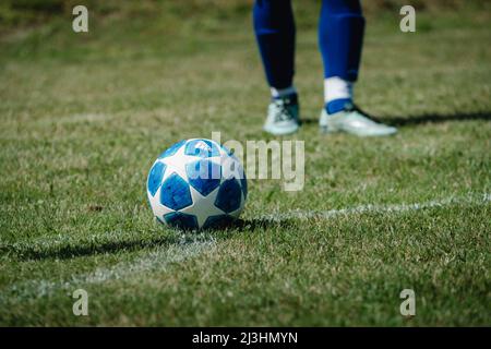 football lying at the corner, soccer player boots in the background Stock Photo
