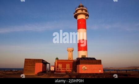 Spain, Canary Islands, Fuerteventura, west coast, Punta de Toston, evening light, view on red-white striped new light tower and old lighthouse house, sky blue with white clouds