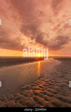 Seascape showing beach at low tide and sunset with cloudy sky over the Wadden Sea, North Frisia / Nordfriesland, Schleswig-Holstein, Germany Stock Photo