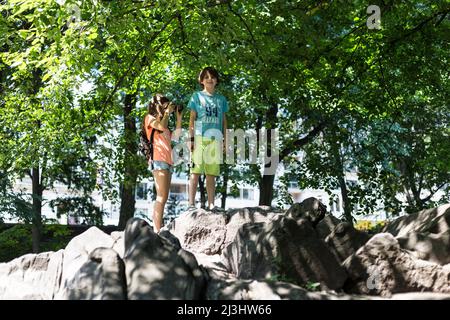 5th Av & W 58TH Street, New York City, NY, USA, Young Boy and Girl at Central Park 14 years old caucasian teenager girl and 12 years old caucasian teenager boy - both with brown hair and summer styling at central park Stock Photo