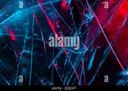 Close-up photo texture of blue and red toned broken and cracked glass on black backdrop. Stock Photo