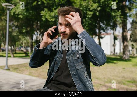 Young man in pessimistic thoughts, he puts his hand on his head and questions his life, sad and thoughtful young man having a discussion with his girl Stock Photo