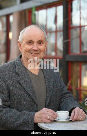 Portrait of smiling gray haired man standing in garden drinking coffee Stock Photo