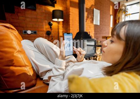 Woman using smart phone with running delivery application at home Stock Photo