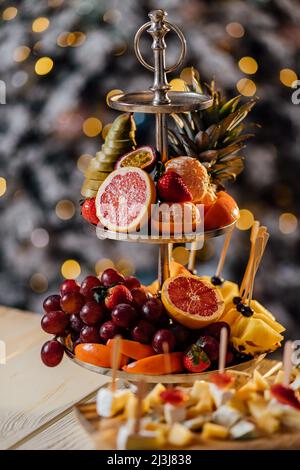 beautiful ripe tangerines lie in a plate on the table close-up with blurred background on the background of a Christmas tree decorated with garlands a Stock Photo